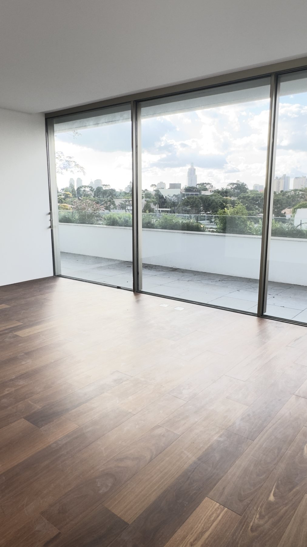 Sala da cobertura com piso de madeira e portas de vidro para o terraço