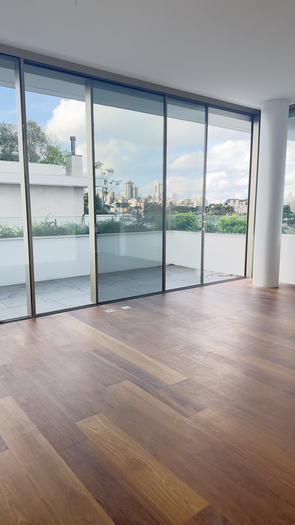 Ambiente com piso de madeira e vidro do piso ao teto