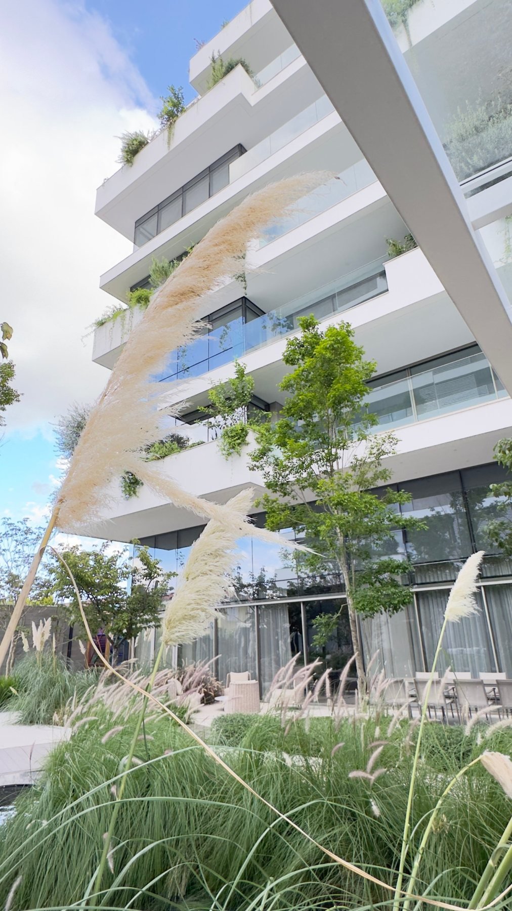 Fachada do Edifício Hanami com varandas ajardinadas e capim-dos-pampas em primeiro plano